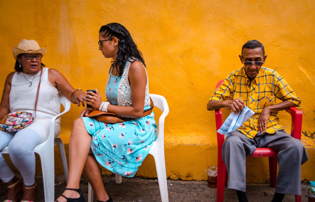 People sitting in front a yellow-painted wall - Getsemani