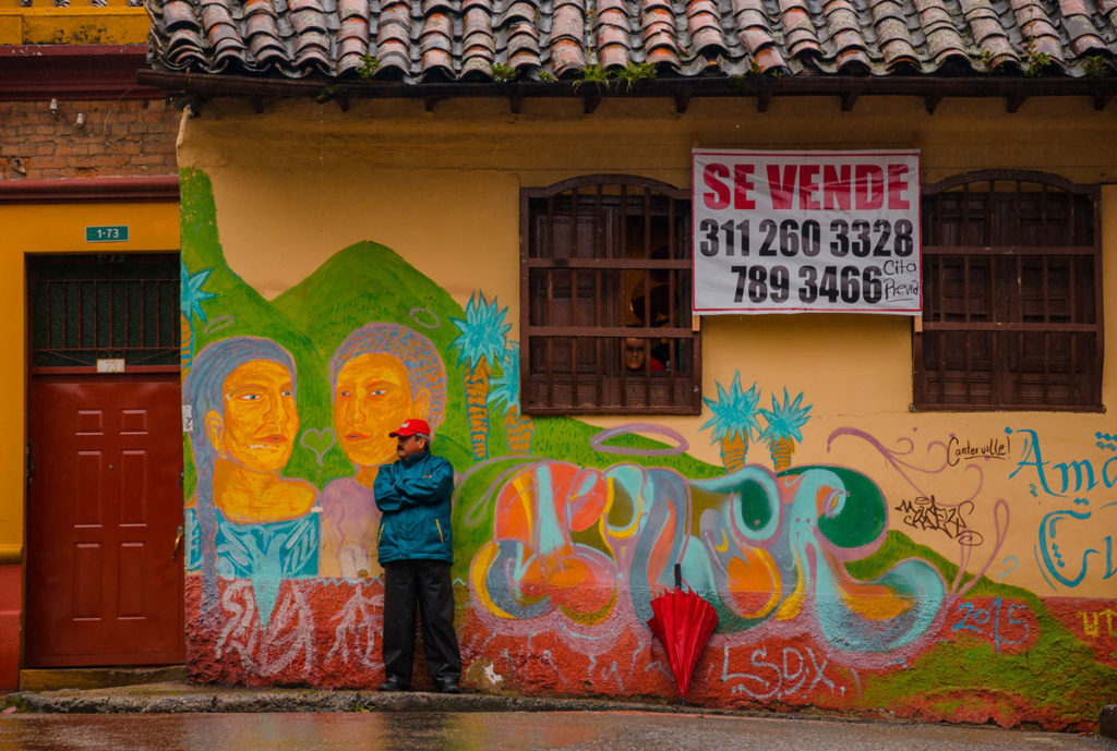 Man on red hat in front of a graffiti - Bogotá