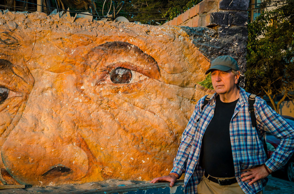 Ed in front of a mural of a man's face - Peru