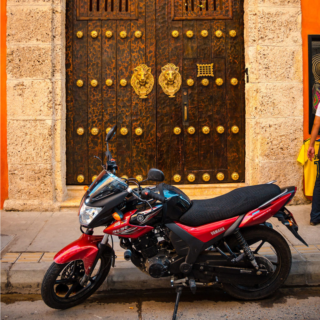 Motorcycle parked in front of an old, ornate door - Cartagena