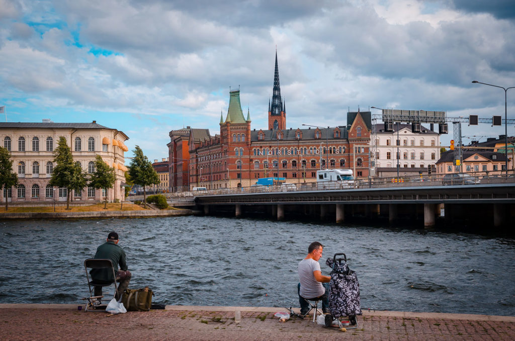 Two men fishing on the side of the waters facing the Central Bridge