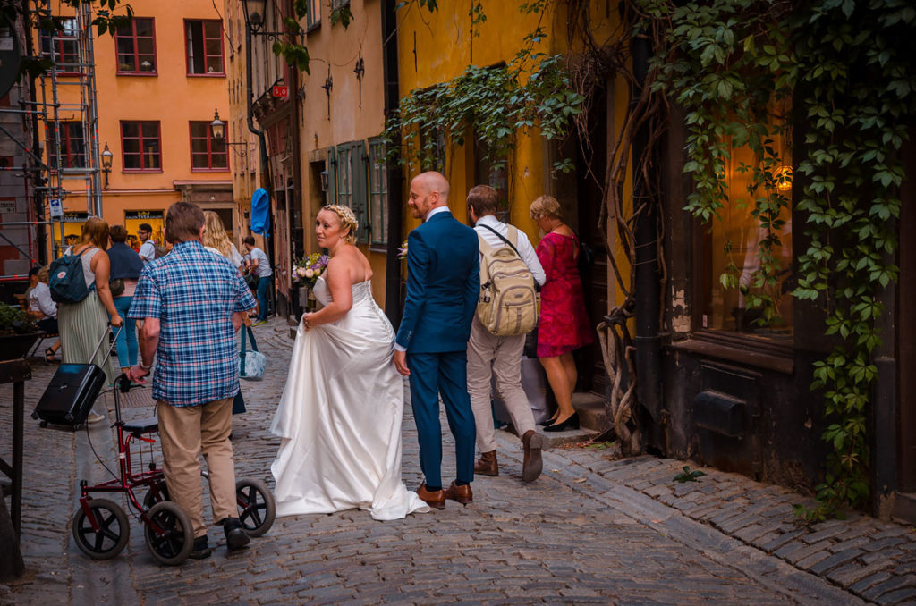 A bride and her groom along with other people walking on a cobblestone street