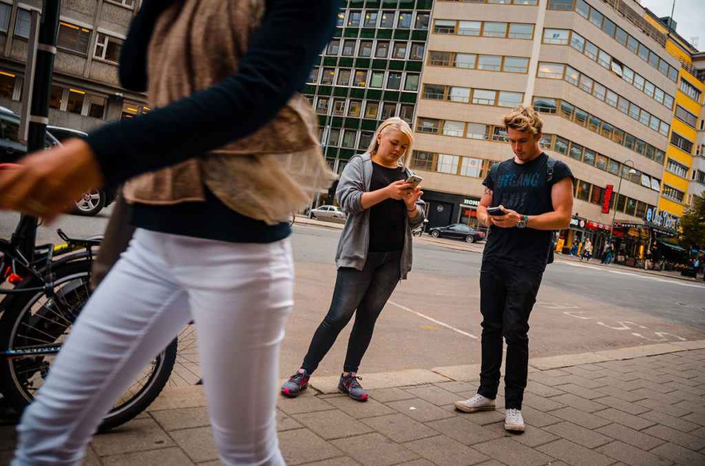 Young man and woman on mobile phones on the street - Oslo