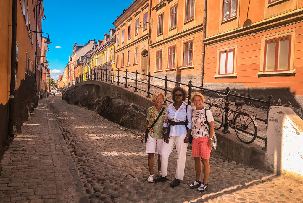 Khadija, Britta, Kristin in front of a row of colorful buildings along a street