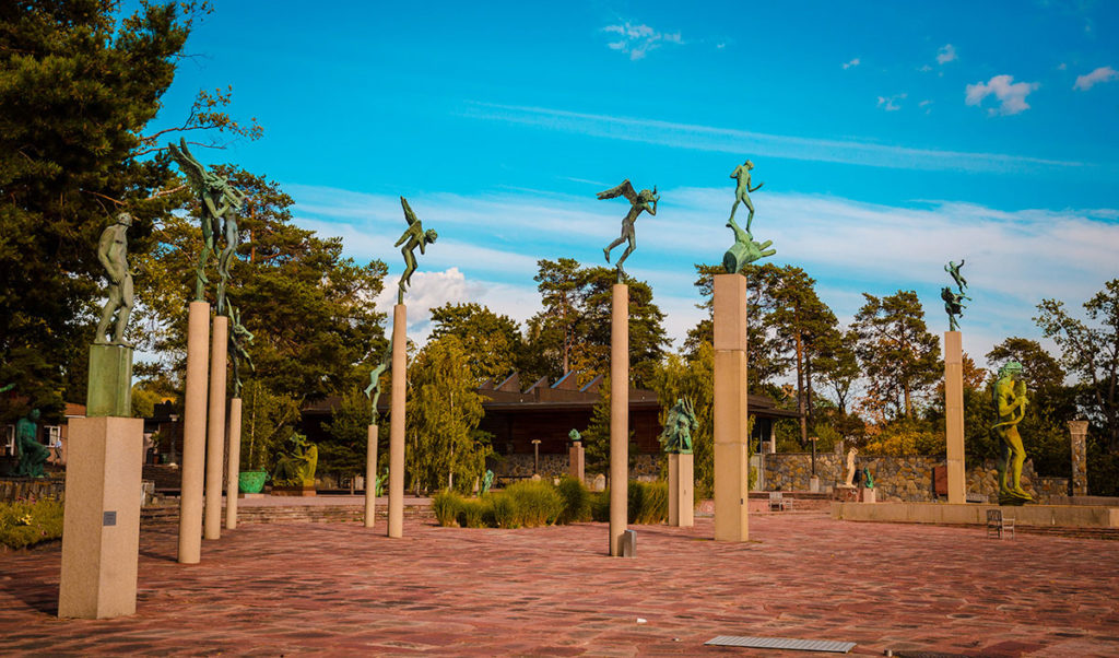 Statues of men and angels atop columns in the Millesgården 