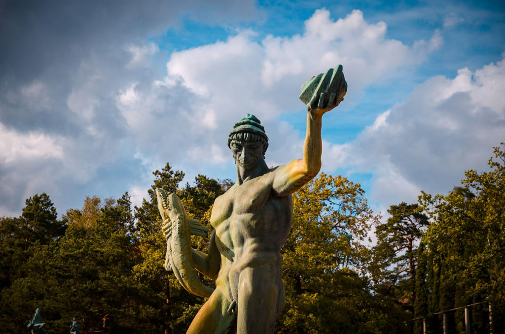 Faded bronze statue of Poseidon holding a fish in Millesgarden