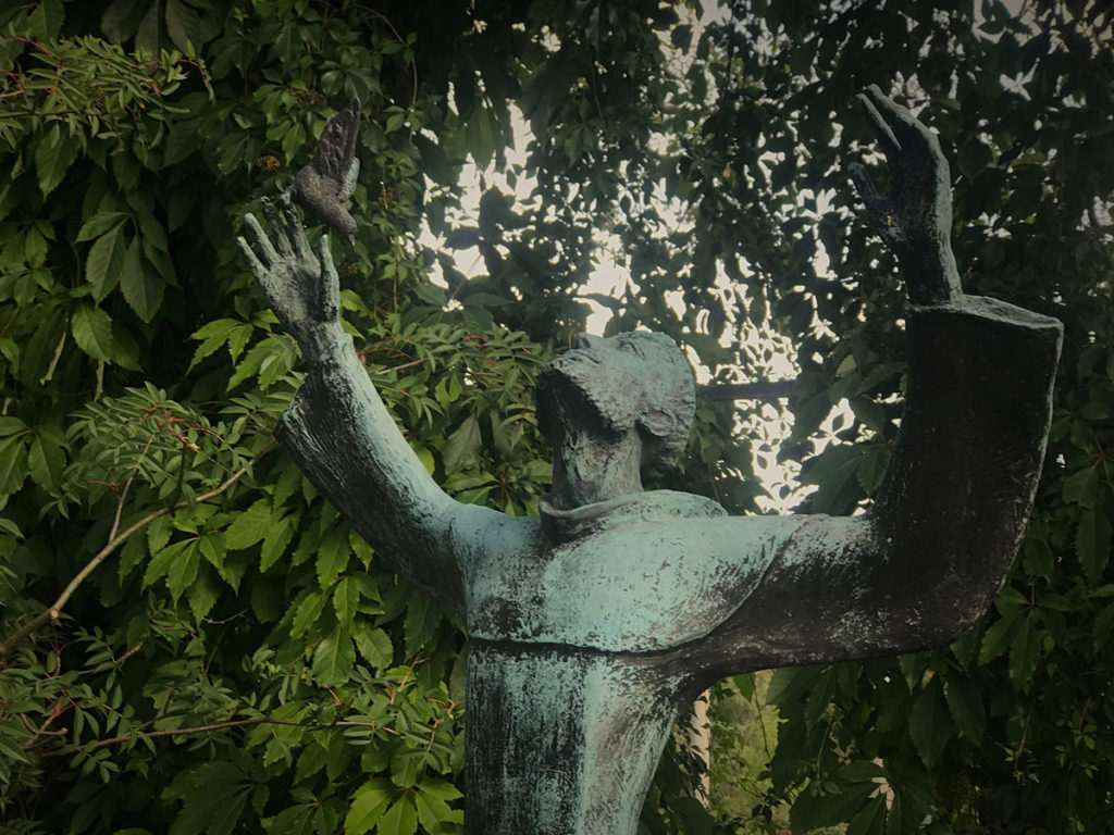 Statue of a priest raising both hands to pray