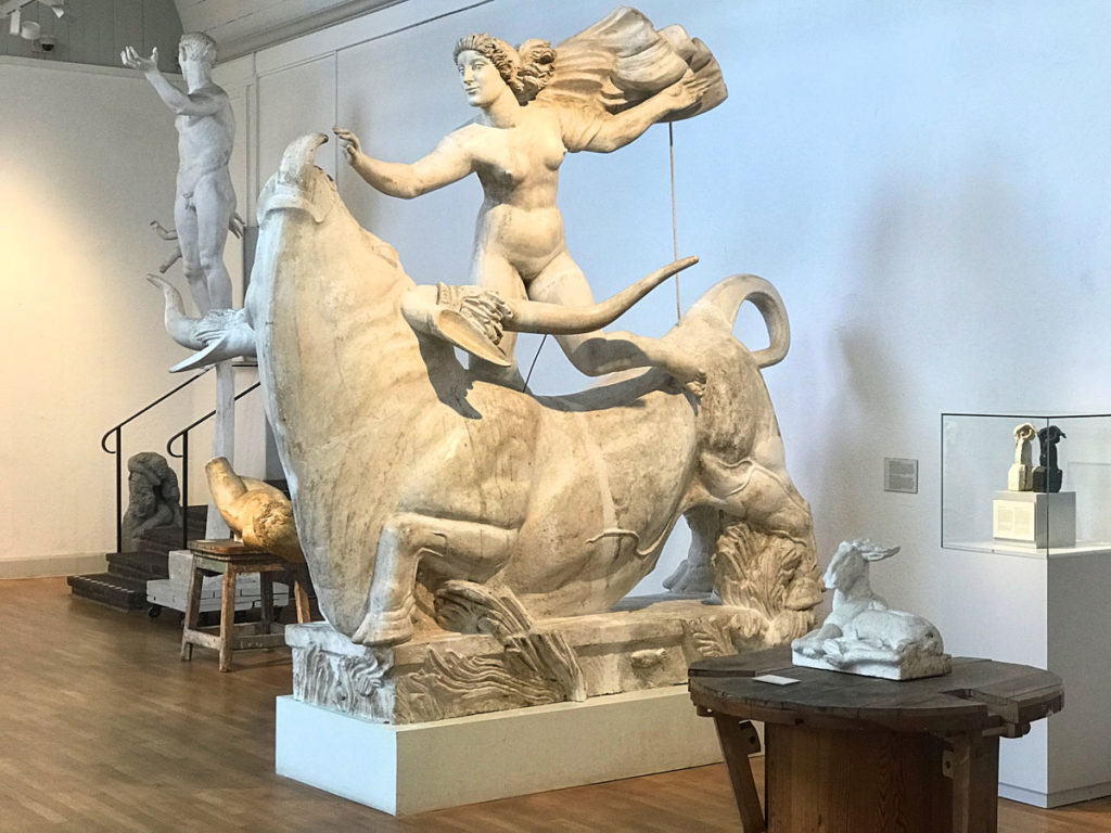 White statue of a man holding a cloth on top of a bull 