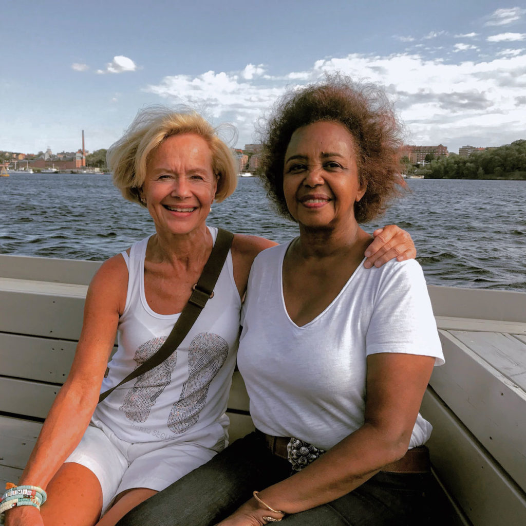 Khadija with her friend Britta smiling and sitting along the harbor