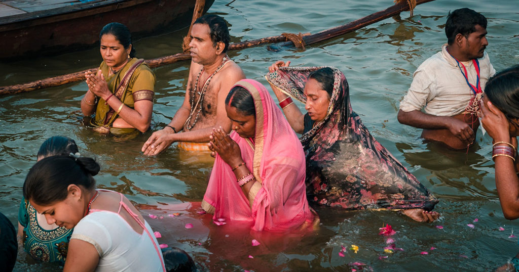 Hindu pilgrims praying while bathing in the river - India