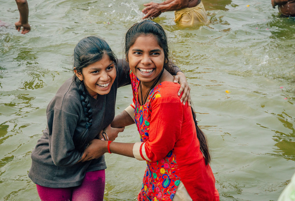 Two laughing young women bathing in the river - India