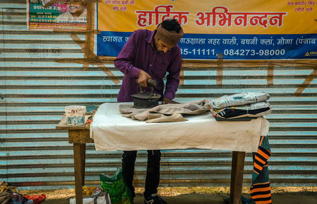 Man ironing clothes during Kumbh Mela - India