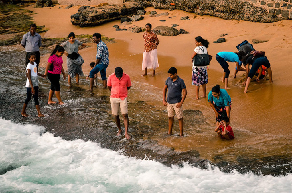People dipping their feet in the water - Galle Face Beach
