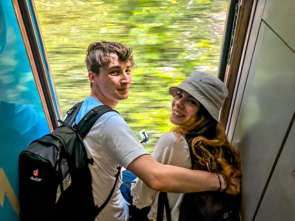 Young tourist couple sitting on a moving train's door - Sri Lanka