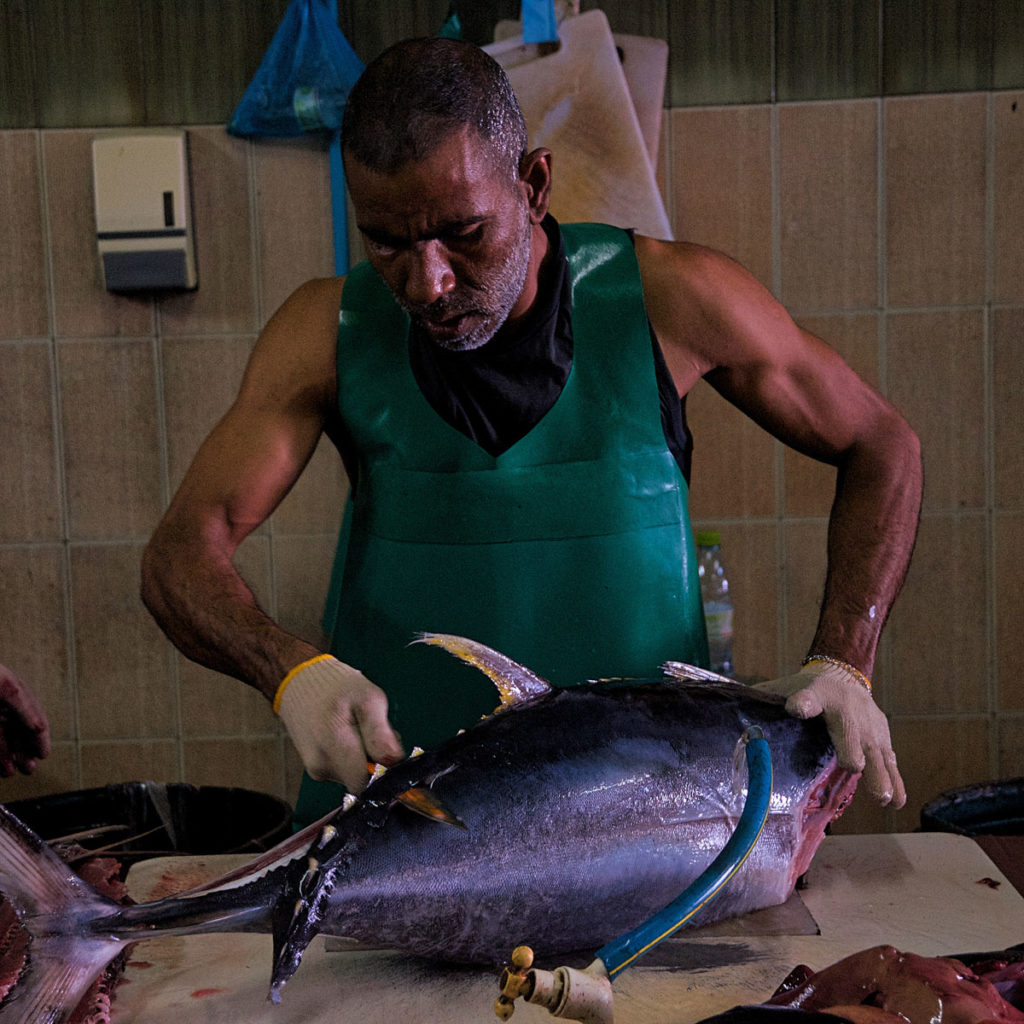 Fish vendor slicing fish - Malé