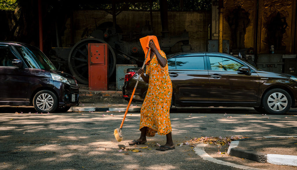 Lady street sweeper in orange clothes - Colombo